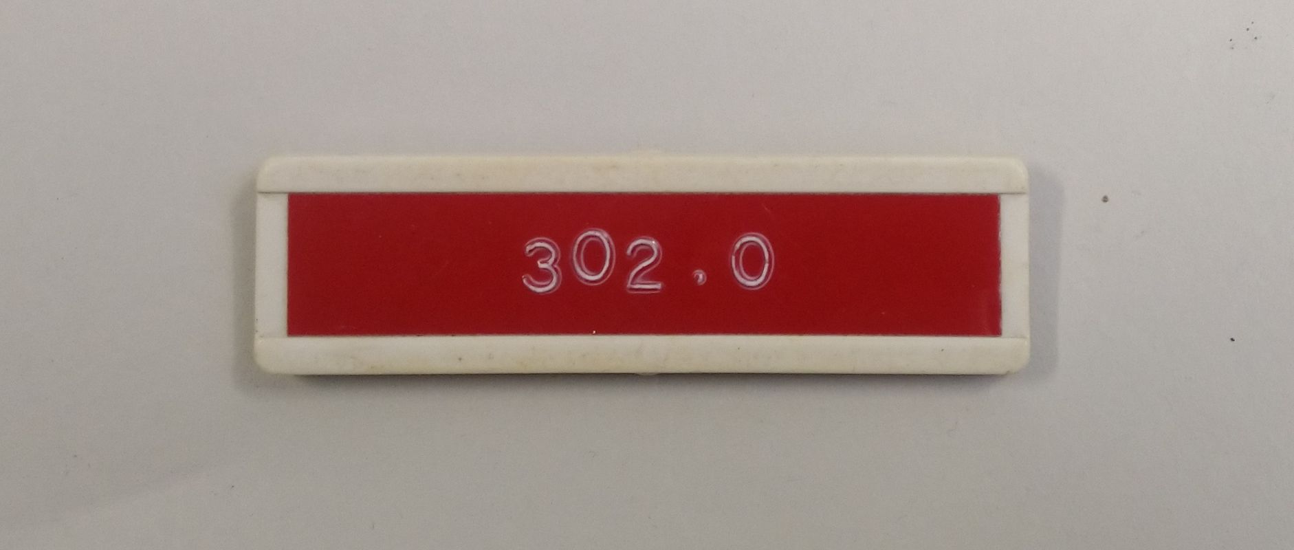 Photograph of an old NHS name badge with the numbers 302.0 printed on it.