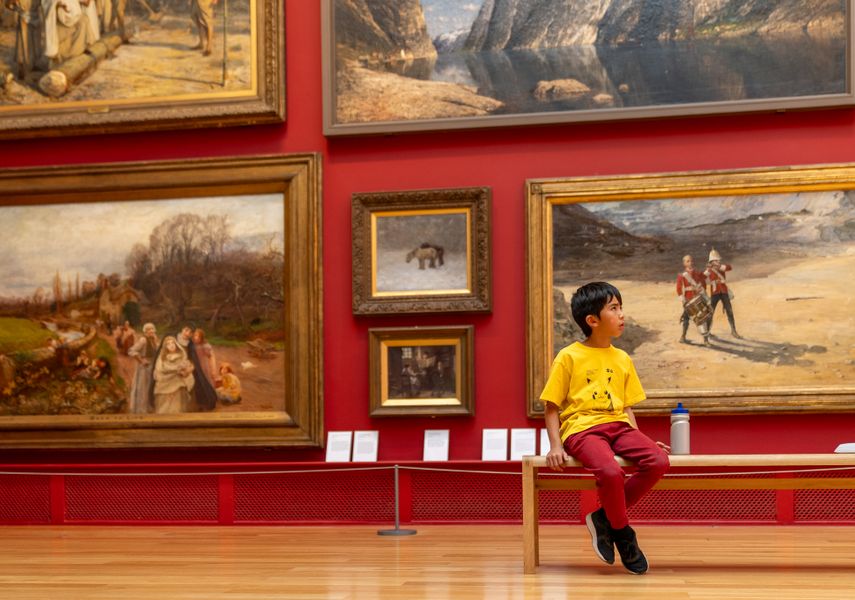 A child sits on a bench in an art gallery