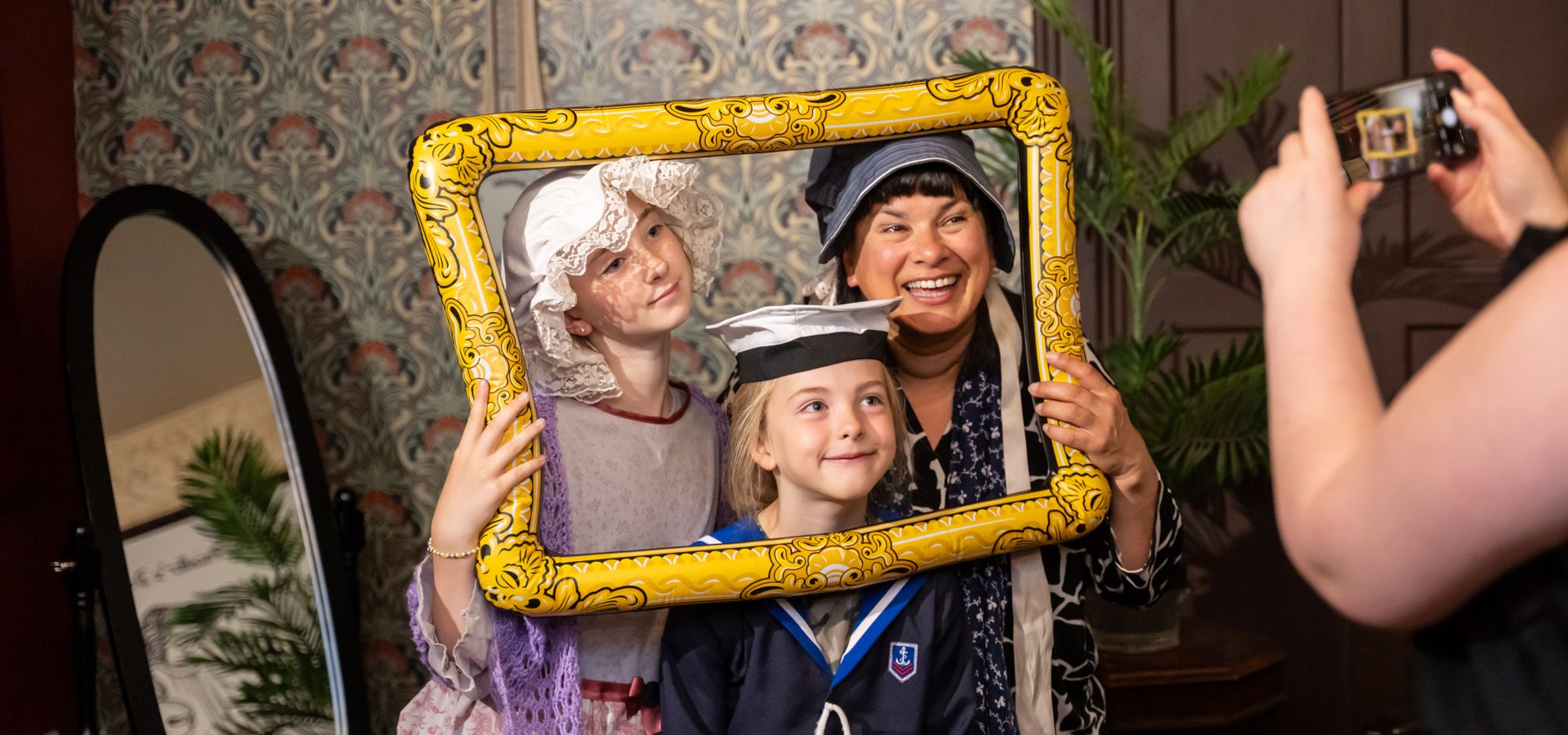 An adult and 2 children in fancy dress holding an inflatable frame posing for a photo