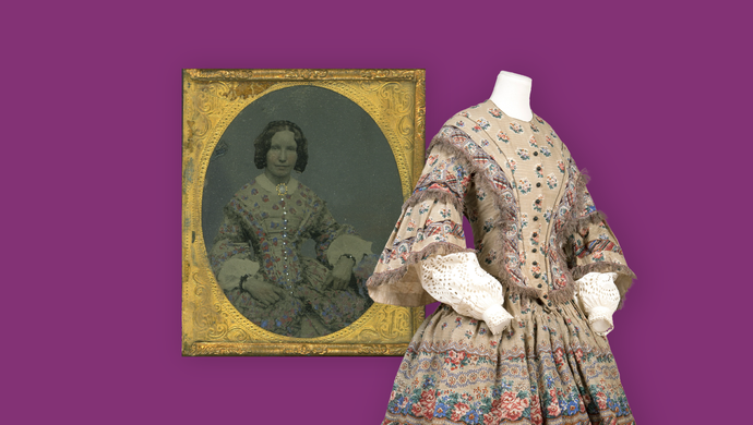 A purple background with a mannequin with a Victorian dress on and a framed photograph of a woman wearing the dress