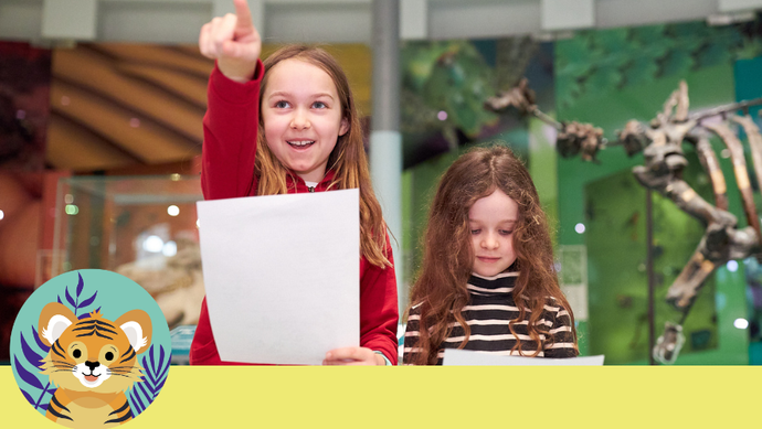 Two children holding trail sheets, with an animal skeleton display behind