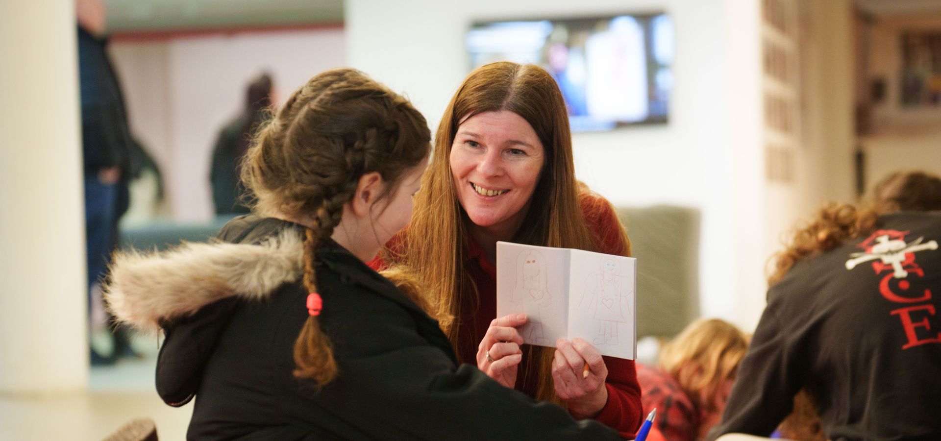 An adult showing a drawing booklet to a group of students sat on bean bags