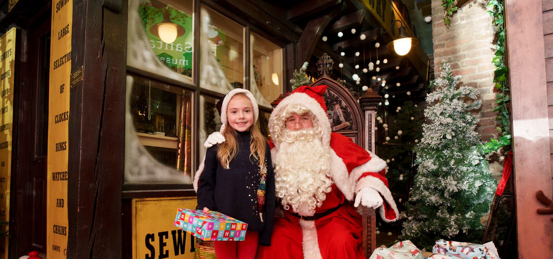 Santa and child posing outside a Victorian shop
