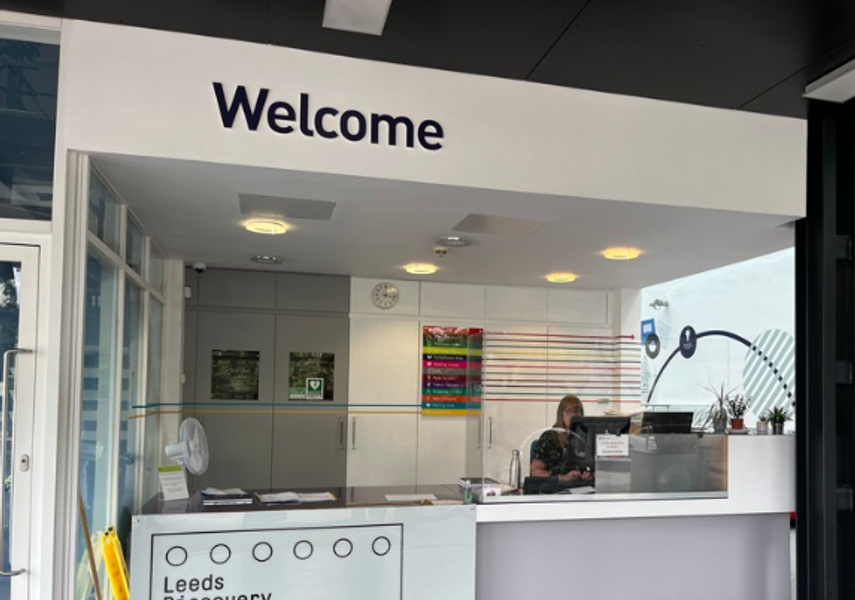 A white welcome desk in the foyer of Leeds Discovery Centre