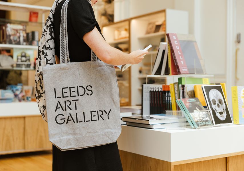 A person shopping in Leeds Art Gallery carrying a Leeds Art Gallery tote bag