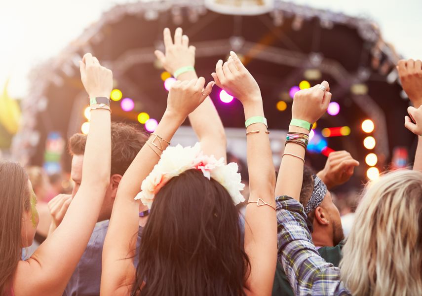 people in a crowd with their hands in the air in front of a stage