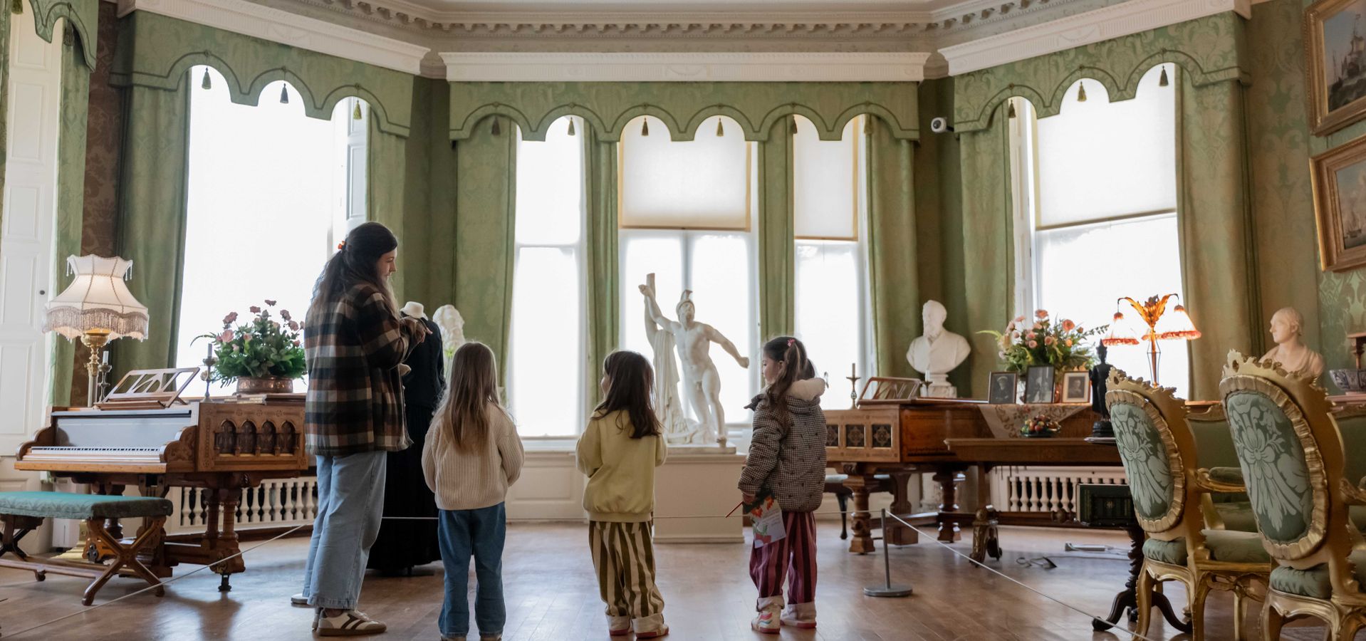 an adult and 3 children looking at the drawing room windows in Lotherton House