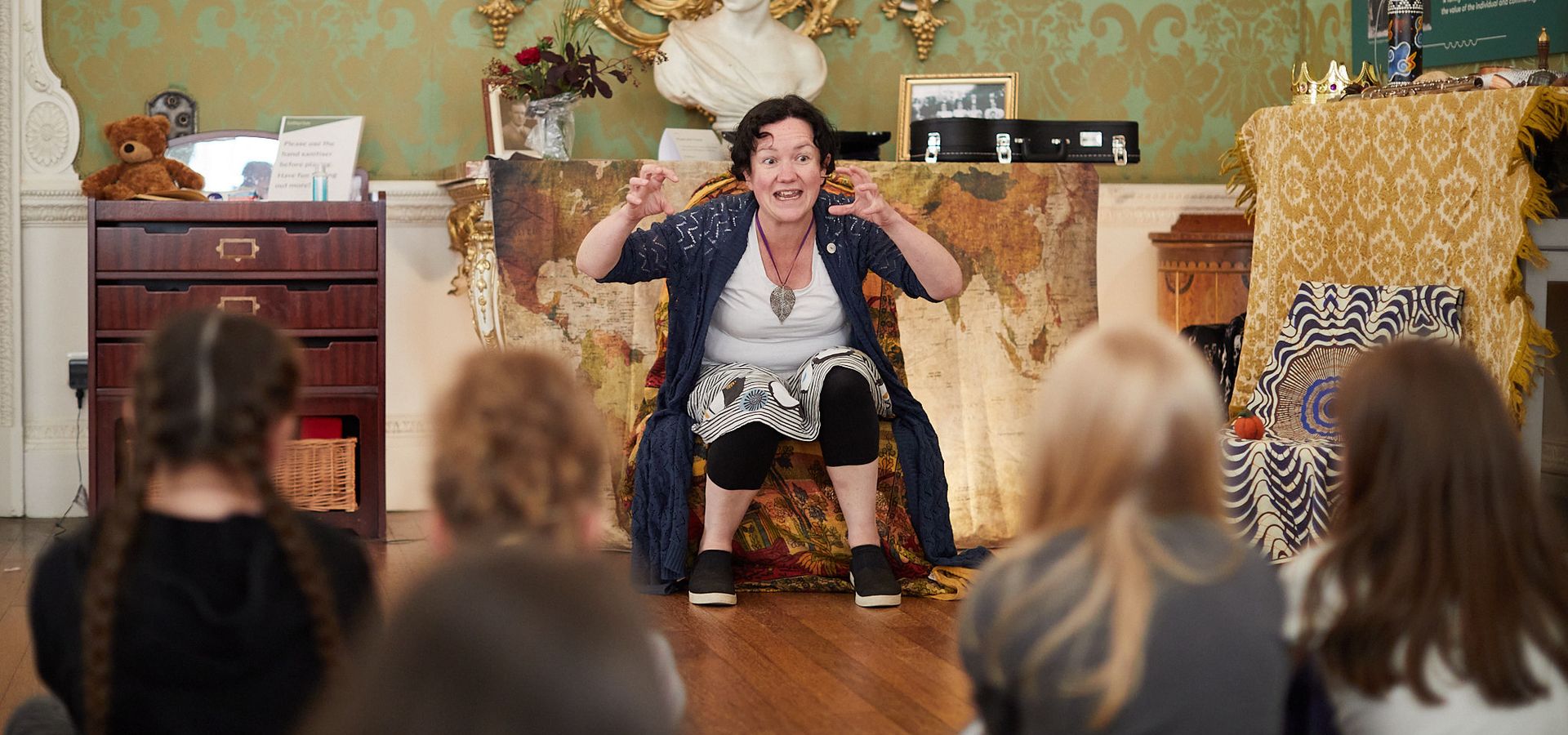 A storyteller tells a story to a group of seated children.