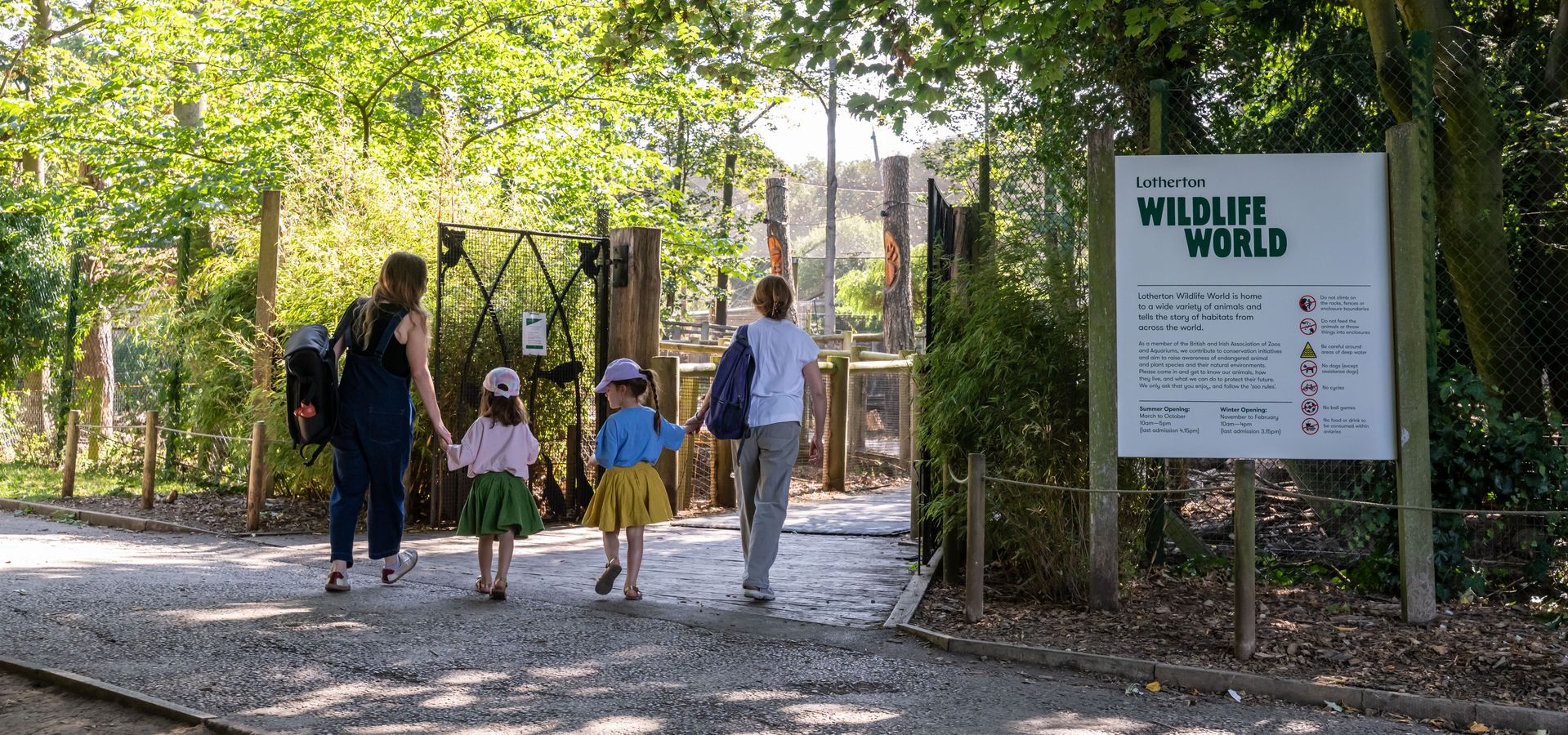 Two adult and 2 children walking into the entrance of Wildlife World