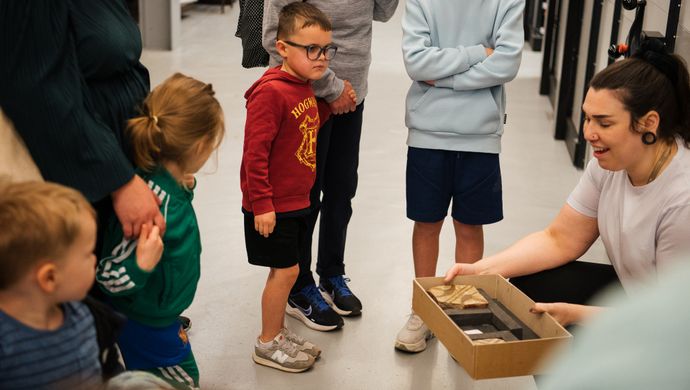 A curator holding a box of ancient tiles in front of a tour group