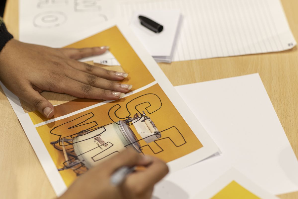 Two hands writing on a collaged zine