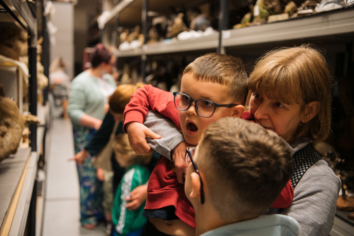 an adult holding a child up to look at an object