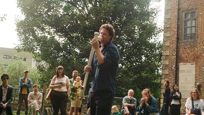 A person using a drain pipe as a musical instrument outdoors