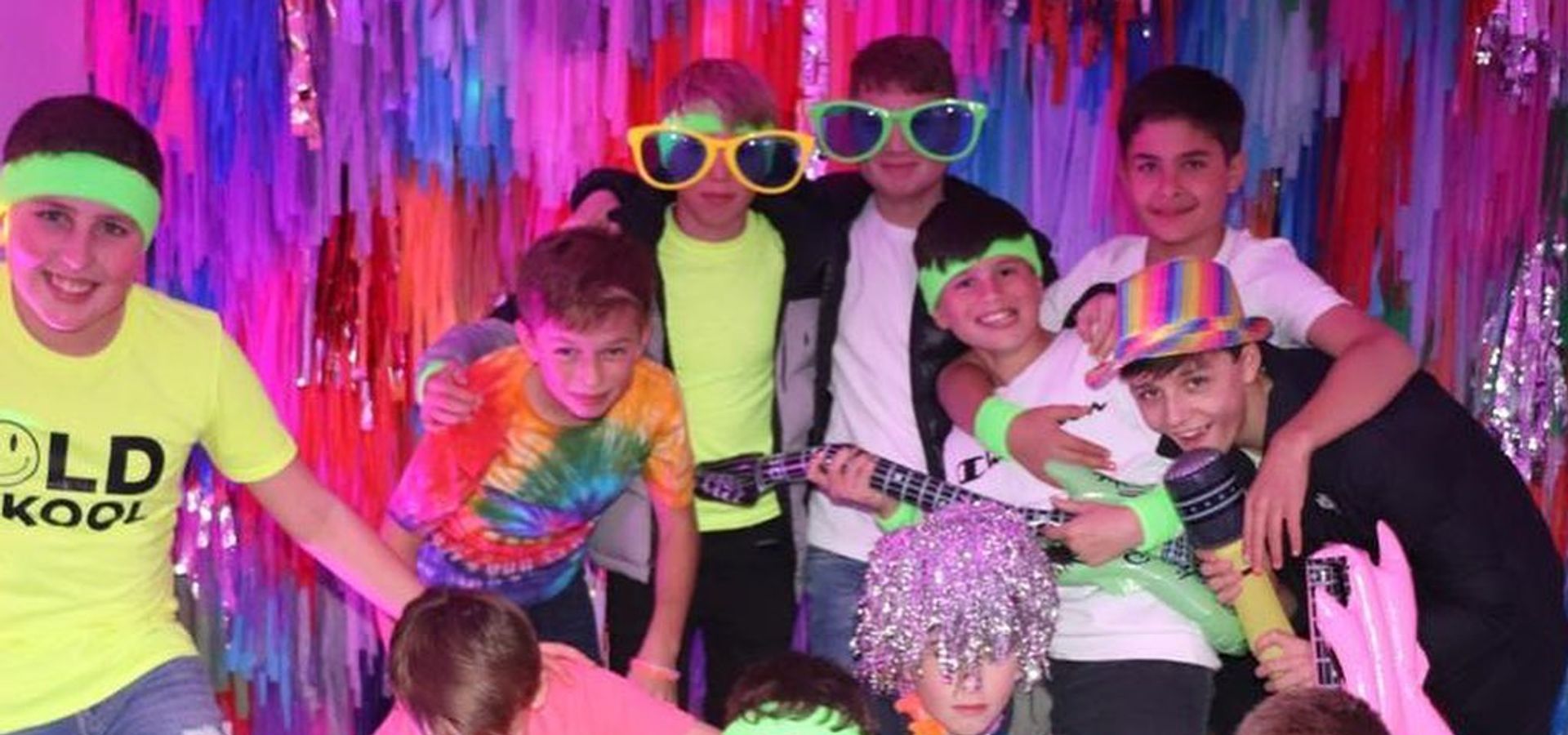 A group of children posing with fun props and wearing neon clothing