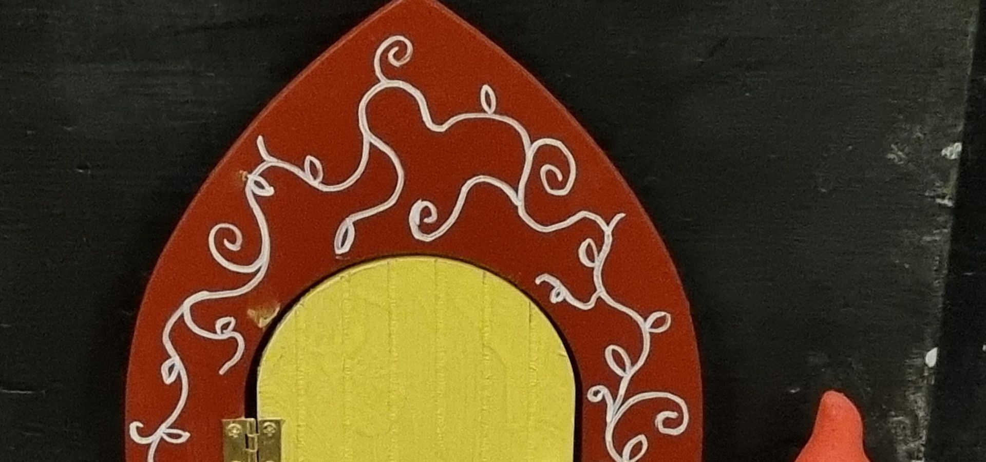 A little gnome door with a gnome with a orange hat on it next to the door