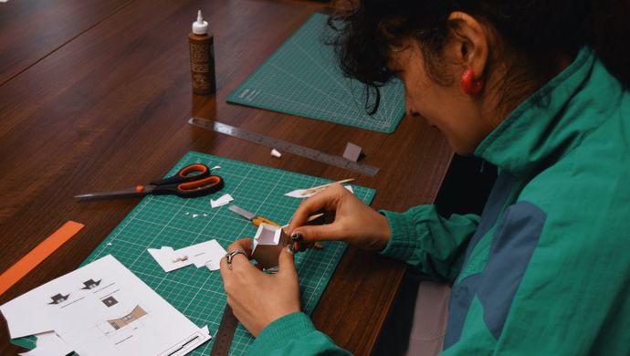 A adult working on paper crafts on a table