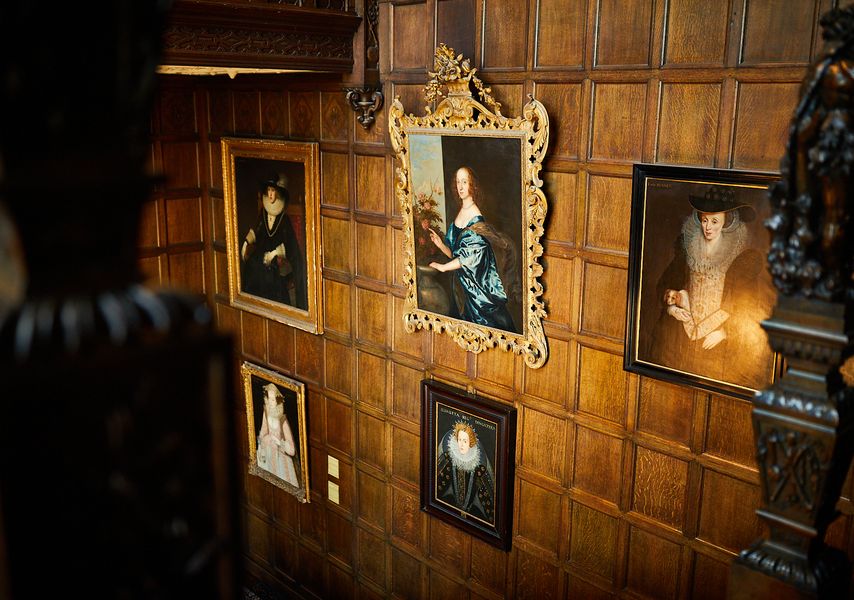 A wooden panelled stairway with 5 framed paintings on