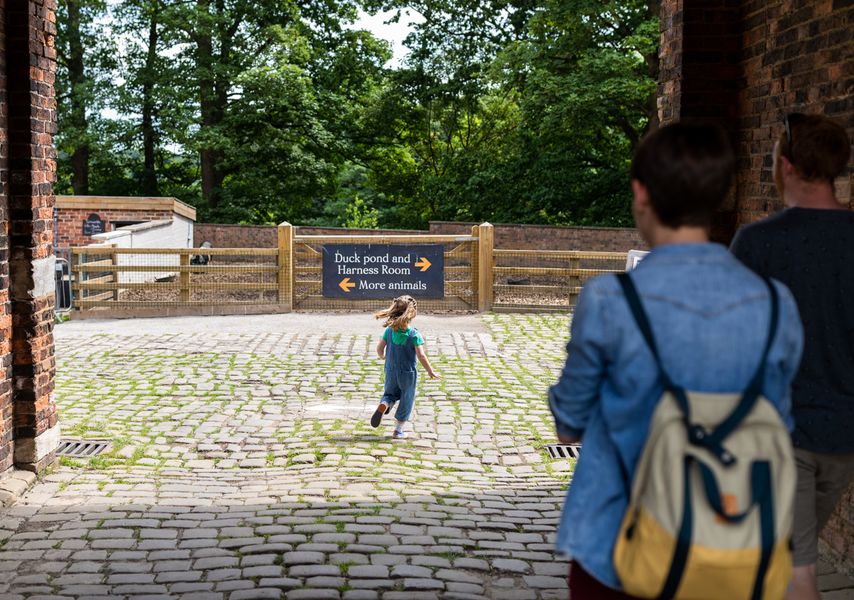 A child running through Home Farm's cobbled path, with a parent watching