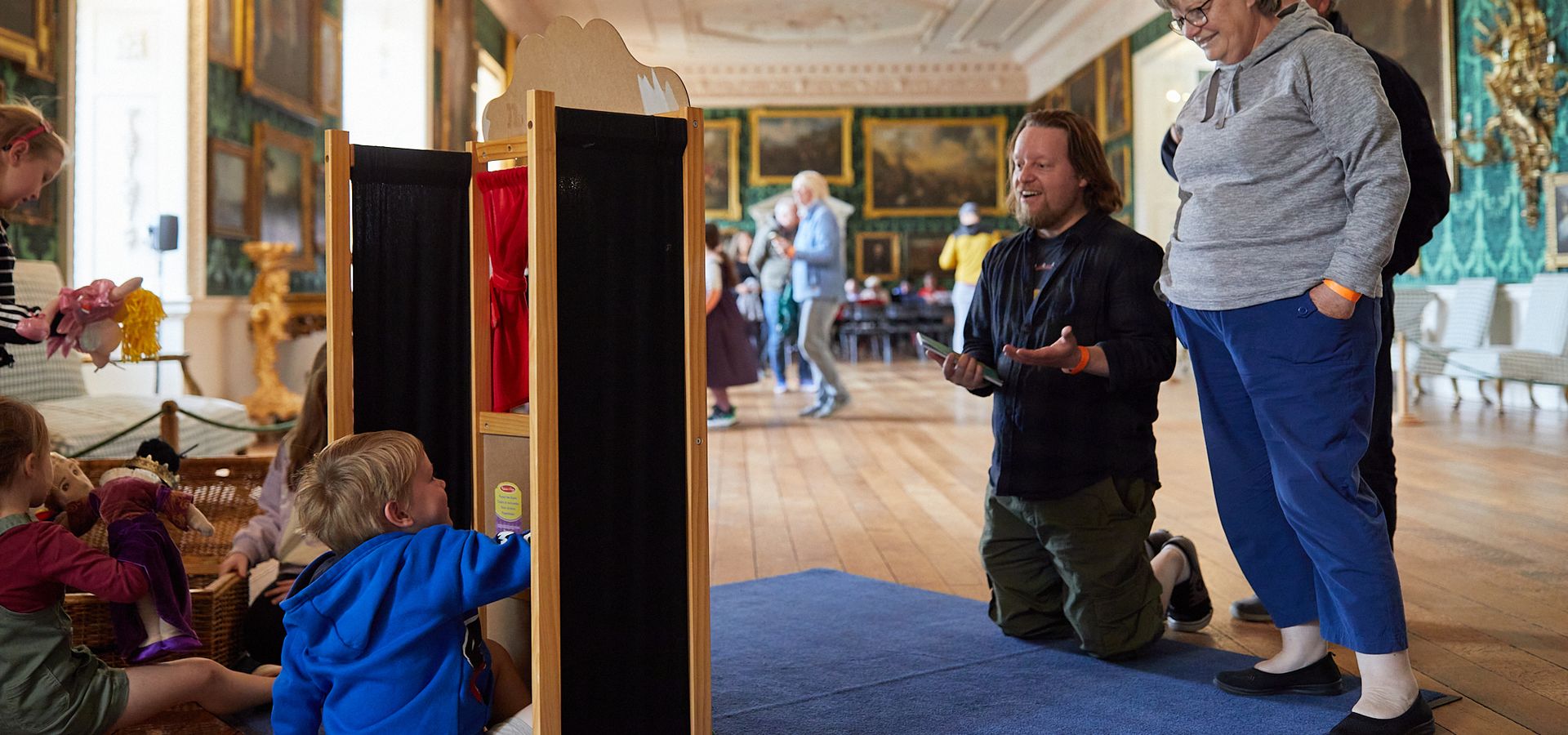 A family watching children play in a puppet theatre in Temple Newsam