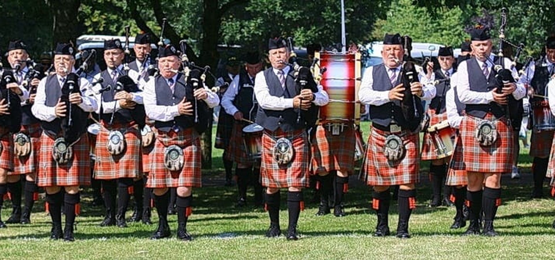 Group of people playing bagpipes dressed in kilts