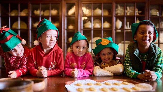 A group of children in elf hats making Christmas biscuits