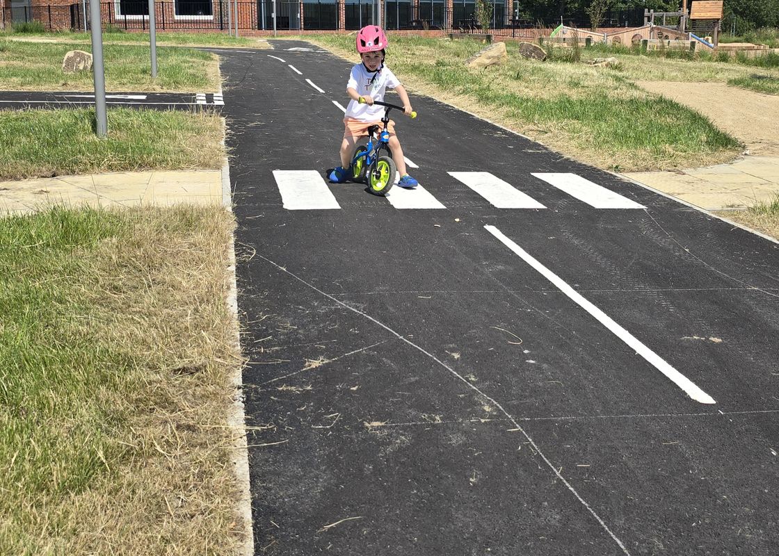 Children scootering and biking on the learn to ride area