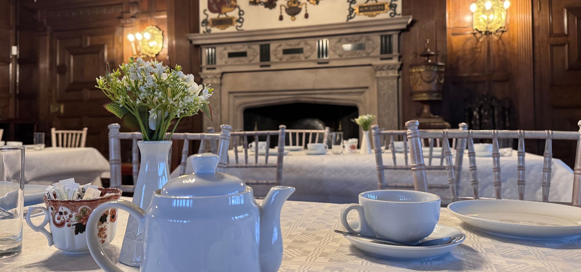 A tea pot and tea mugs on a table infront of a fire place at Temple Newsam