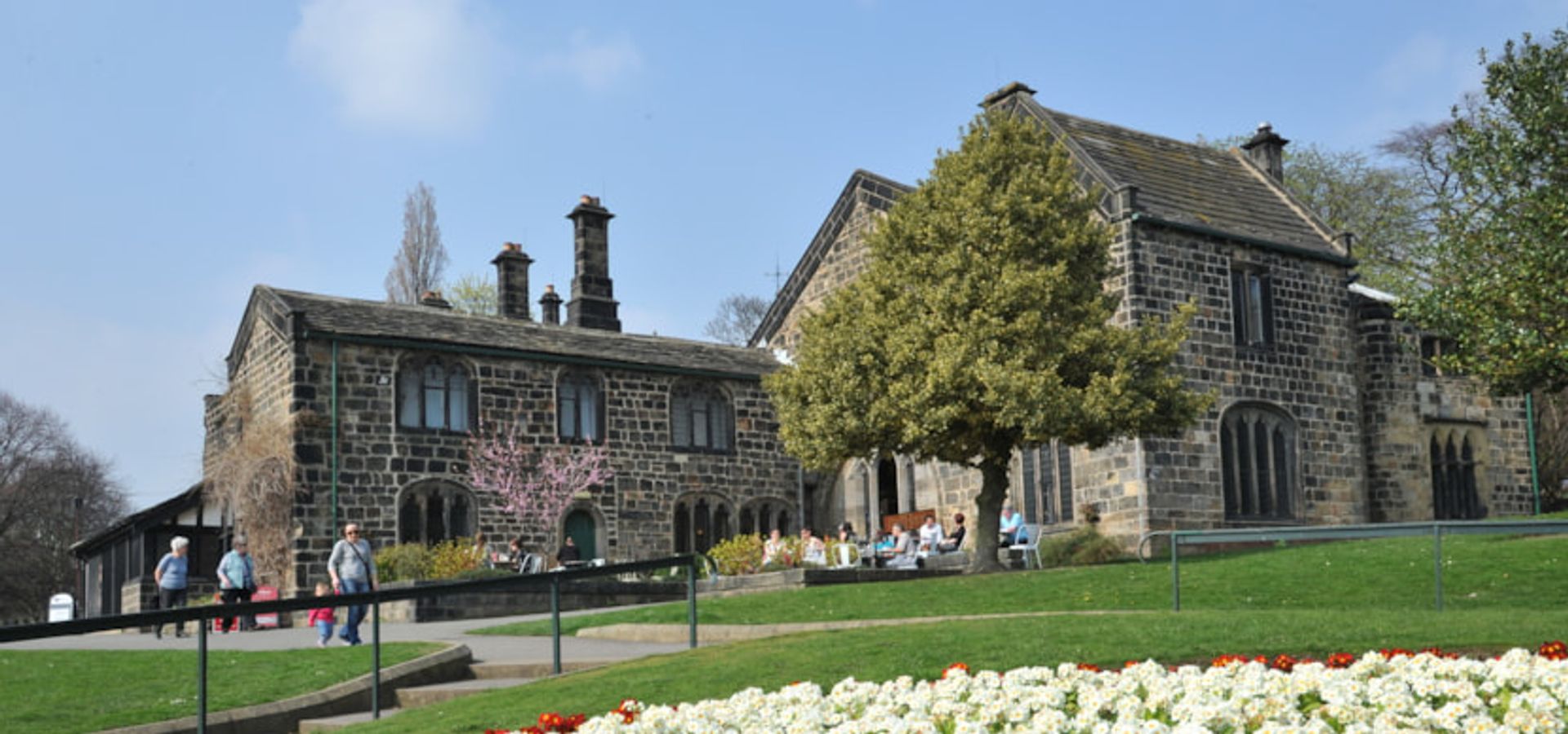 A victorian museum on a hill with a circle of flowers in front