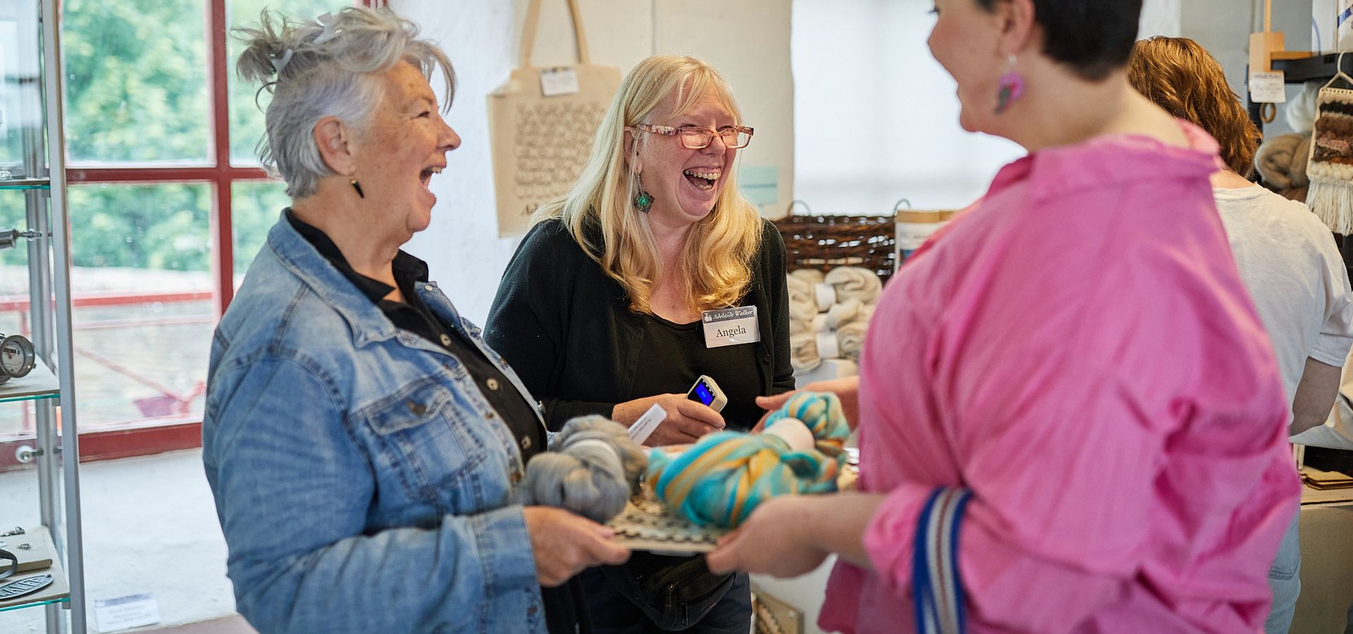 People holding balls of wool and laughing